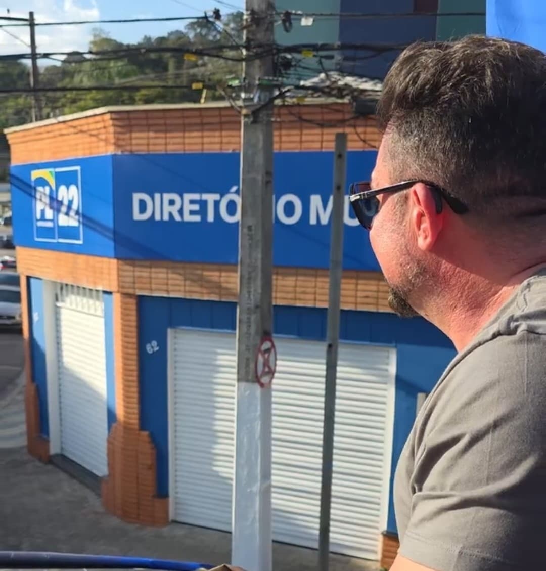 Delegado Sandro em cima do caminhão de som iniciando a carreata da campanha com fundo o diretório do PL